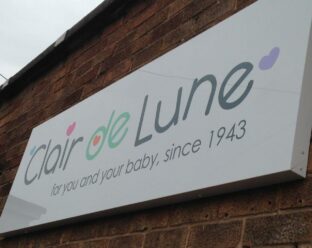 Wall sign for "Clair de Lune" with the tagline "for you and your baby, since 1943" on a brick wall.