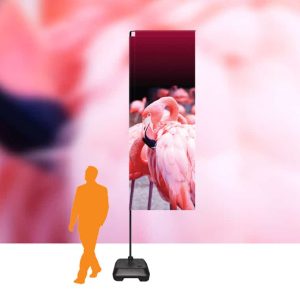 A person silhouette standing next to a tall, colourful sail flag with a flamingo design, set against a pinkish background.