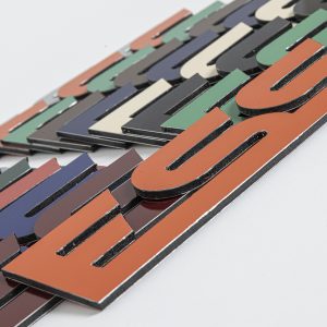 Coloured Aluminium Composite Flat Cut Letters spelling "ESS" arranged on a white background.