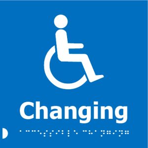 A blue square sign with a white wheelchair icon and a person sitting in a wheelchair, below which the word "Changing" is written in bold white letters, accompanied by Braille dots underneath.