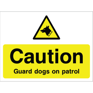 Outdoor warning sign with dog icon and message "Caution: Guard dogs on patrol" in black on yellow background