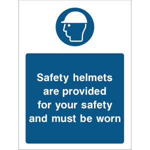 Blue warning sign with an icon of a person wearing a safety helmet and the message “Safety helmets are provided for your safety and must be worn”